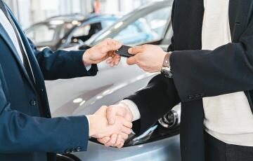 Kunde tauscht sein Fahrzeug bei einem Autohändler in Zürich ein moderner Showroom mit neuen und gebrauchten Autos im Hintergrund